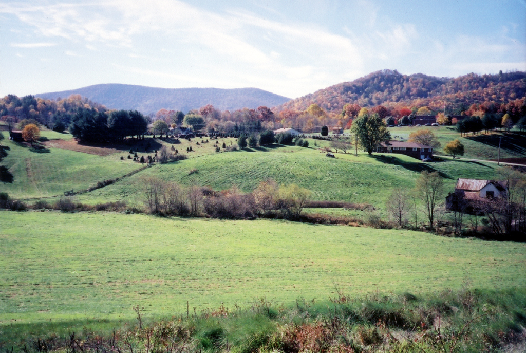 Rolling Appalachian valley with farmland, scattered homes, and ridgelines in peak autumn color, NC High Country